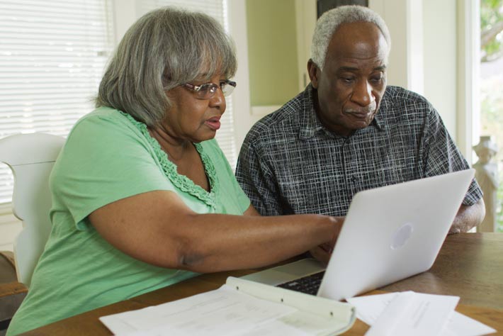 Mature couple comparing notes in front of a computer, like Medicare Advantage Plans. 