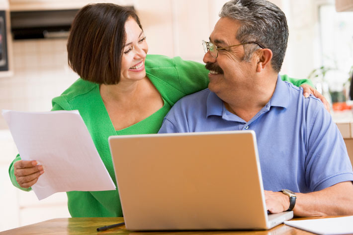 Happy mature couple at computer studying Medicater insurance coverage, like that offered by the Medicare Store by Agency4RED in Lubbock and West Texas.