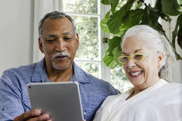 Happy older couple viewing tablet to learn about Medicare insurance.