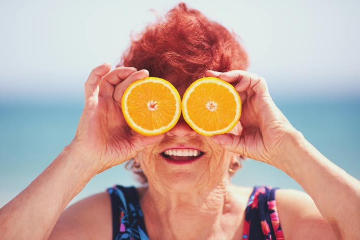 Older retiree enjoying the 'orange zest' of life at the beach, after good retirement planning, like that offered by The Medicare Store by Agency4RED.